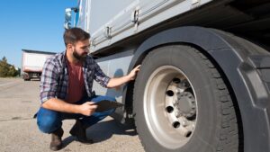 A man inspecting a tire on a semi-truck